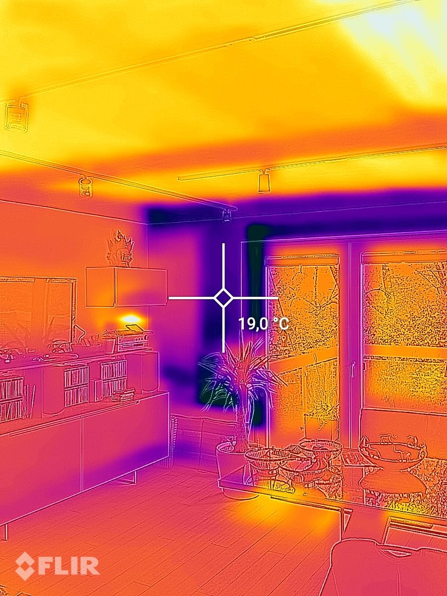 Thermal image of a living room with a warm ceiling from the ceiling heating and a measuring point of 19.0 degrees at the external wall next to the patio door.